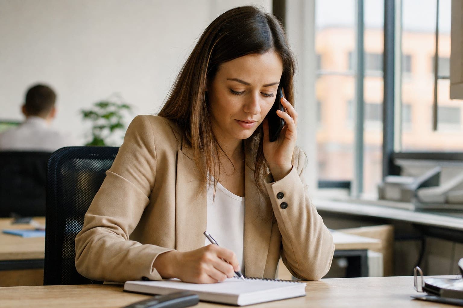 Recruiterin im Telefonat mit Notizblock am Schreibtisch